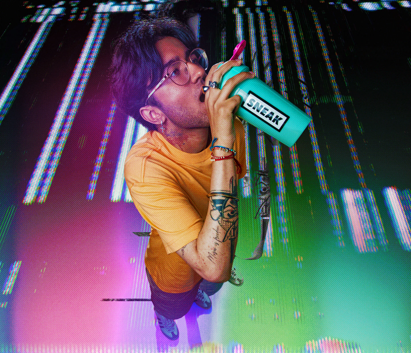 Man with brown hair and forearm tattoos drinking out of sneak shaker
